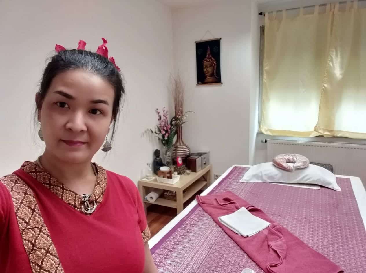 Eine thailändische Masseurin vor einer Massageliege in Stuttgart in einem Massageraum.